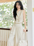 Cream high-rise wide-leg pants with elasticated waist and side pockets.