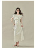 Cream off-shoulder dress with short sleeves and side slit, draped fabric at neckline and waist.
