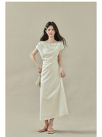 Cream off-shoulder dress with short sleeves and side slit, draped fabric at neckline and waist.