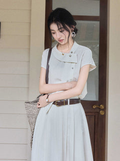 A woman wearing an ivory A-line long dress with a diagonal placket and short sleeves.