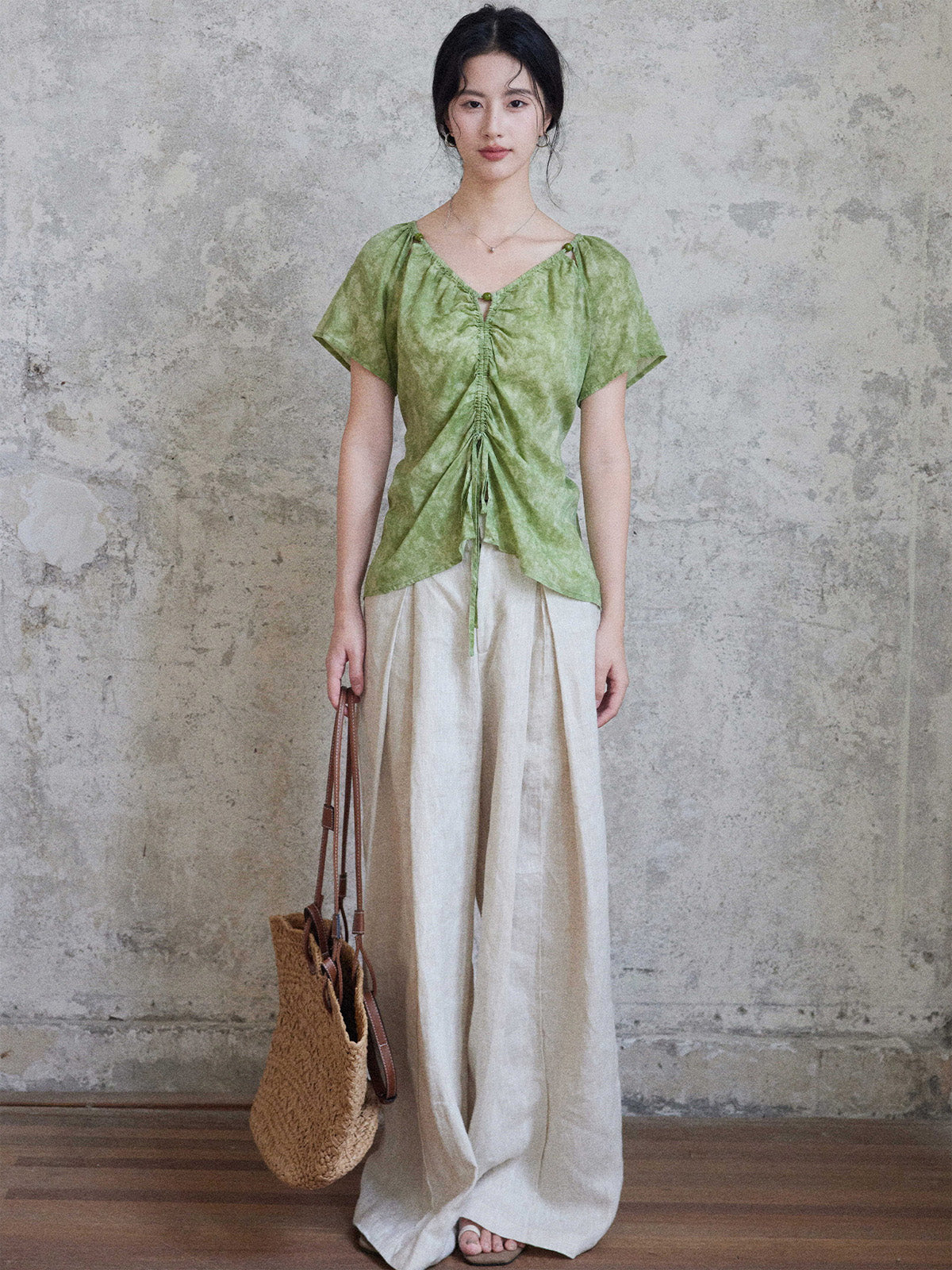 A woman wears a green tie-dye top with a ruched front and short sleeves.