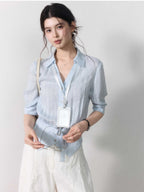 Light blue blouse with collar, button closure, and tied belt at waist.