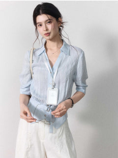 Light blue blouse with collar, button closure, and tied belt at waist.