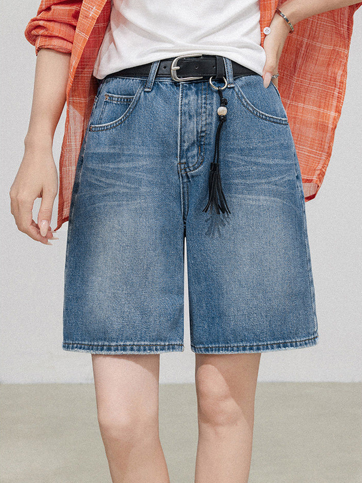 Light blue high rise denim shorts with straight hem and black belt.