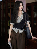 A woman wears a black and white striped layered V-neck top with short sleeves and a cowl neck.