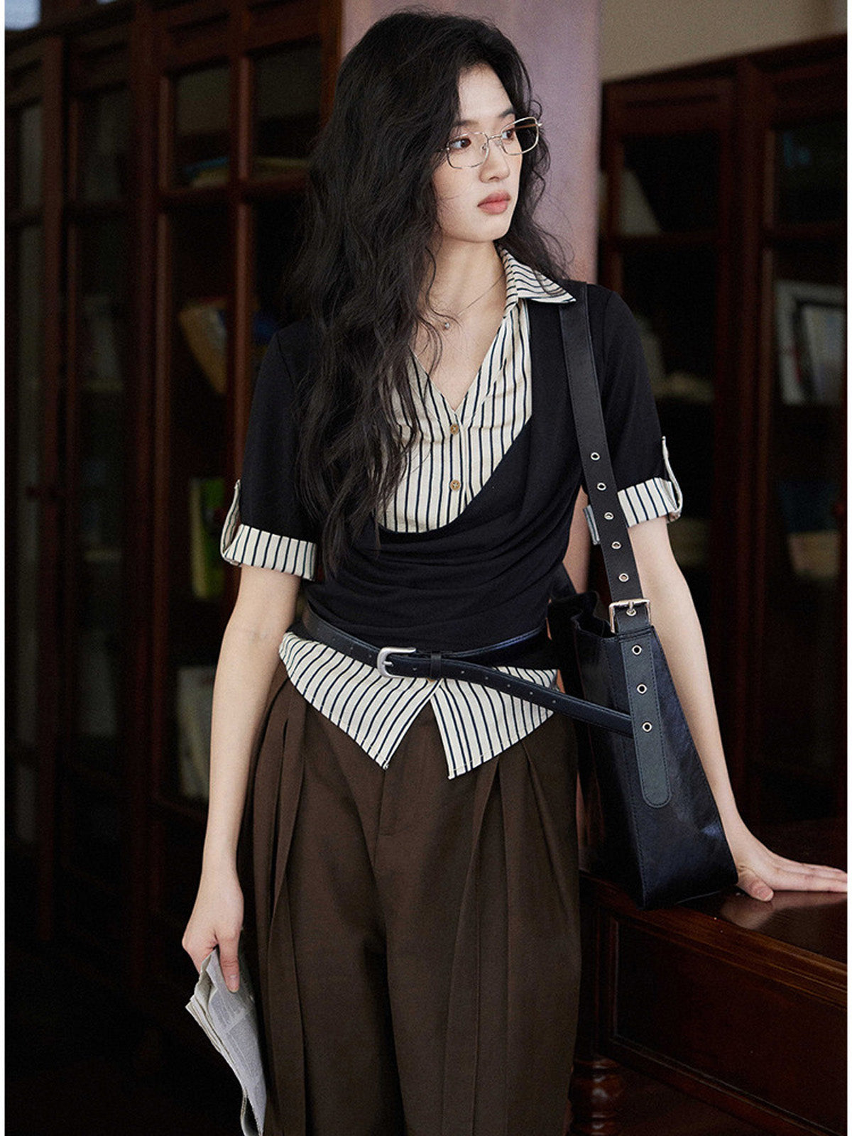 A woman wears a black and white striped layered V-neck top with short sleeves and a cowl neck.