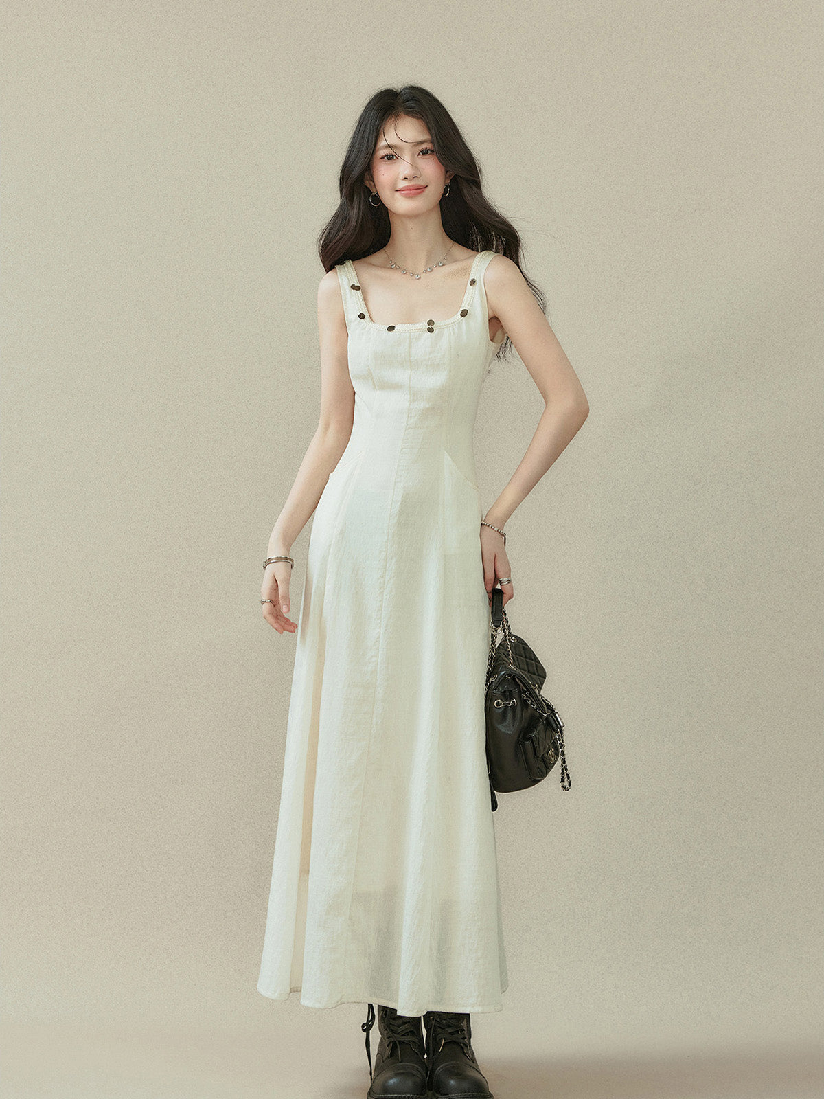 Ivory maxi dress with square neckline and thin straps, featuring button details on the neckline and side pockets.