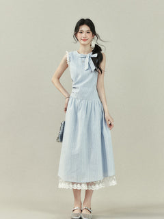 Light blue midi dress with vertical stripes, a bow tie neckline, lace trim on the shoulders and hem, and a gathered waist.