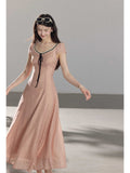 A woman in a pink polka dot dress with lace trim and a black tie at the neckline.