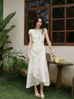 White midi dress with embroidered floral pattern and asymmetrical layered hem.