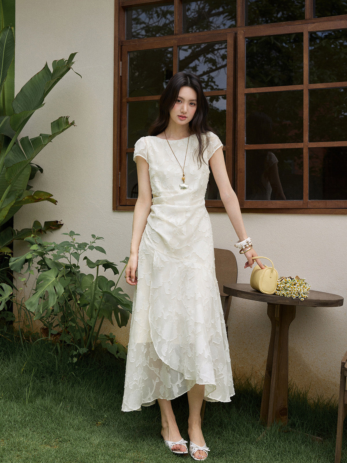 White midi dress with embroidered floral pattern and asymmetrical layered hem.