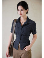 A close-up of a navy striped fitted top with a collar, button-front closure, and cuffed sleeves.