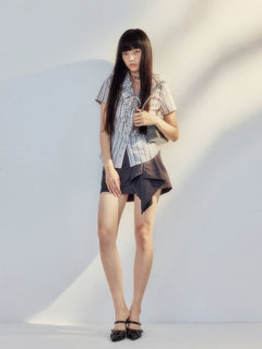 Blouse featuring vertical stripes, ruffled neckline, and asymmetrical hem.