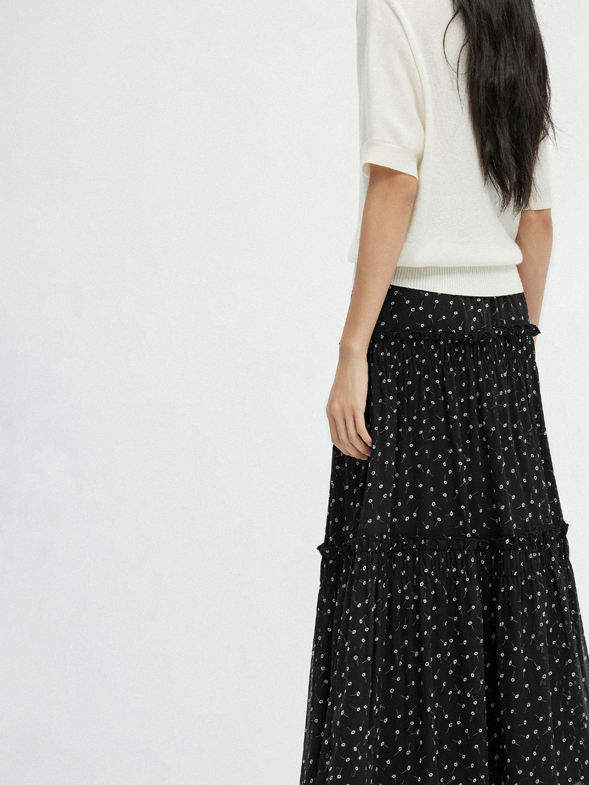 Back view of black floral A-line skirt with layered ruffles and sheer overlay