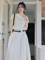 A woman in an ivory A-line long dress, showcasing the side tie detail and pleated skirt.