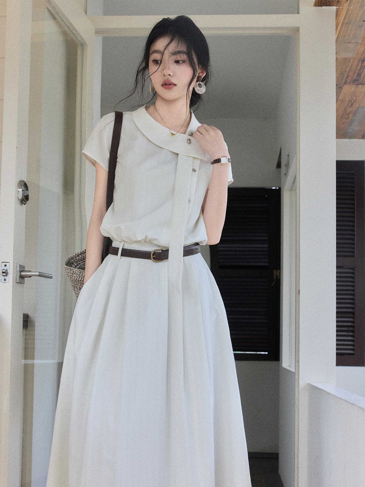 A woman in an ivory A-line long dress, showcasing the side tie detail and pleated skirt.
