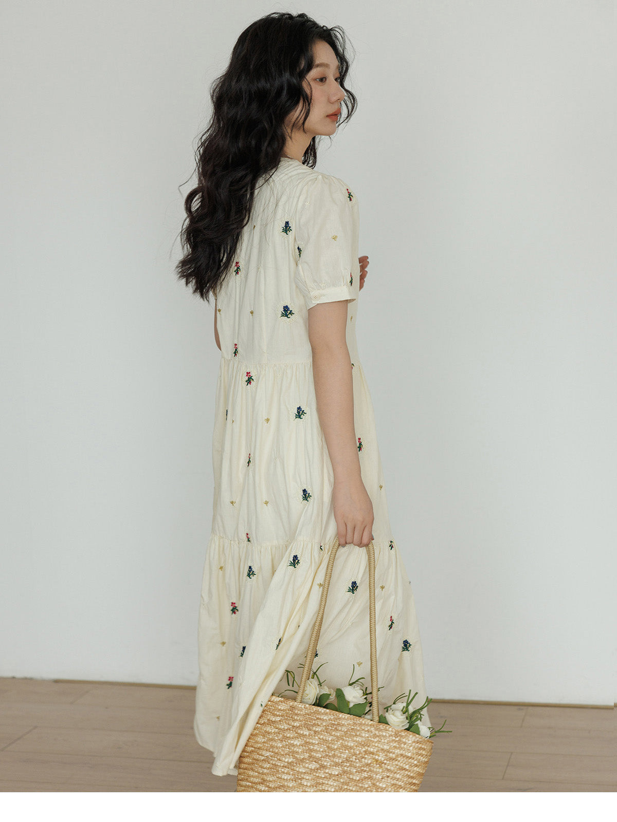 Cream dress featuring embroidered flowers and a gathered waist.