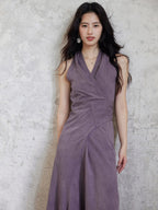 A woman wearing a purple fit-and-flare maxi dress with a V-neck and back tie belt.