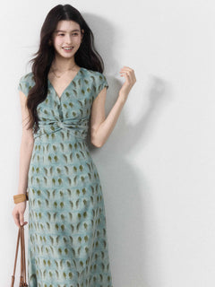 A woman in a long, light blue dress with a green leaf pattern and a V-neckline.
