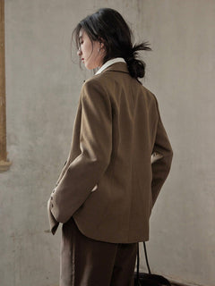 Brown blazer featuring a relaxed fit, double-breasted front, and flap pockets.