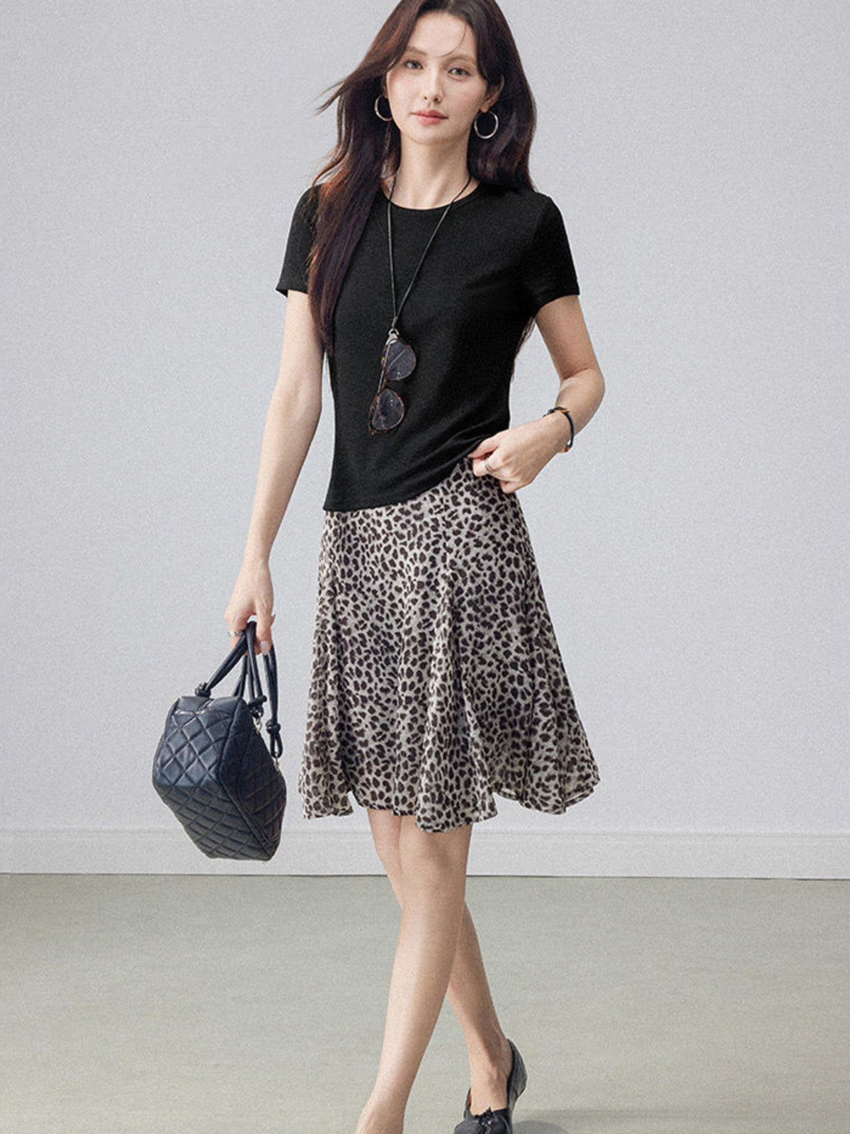 High-waisted leopard print midi skirt featuring an asymmetrical hem and flared silhouette.