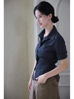 A woman wearing a navy striped fitted top with a collar, button-front closure, cuffed sleeves, and side ties.