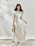 Front view of an ivory polka dot midi dress with short sleeves.