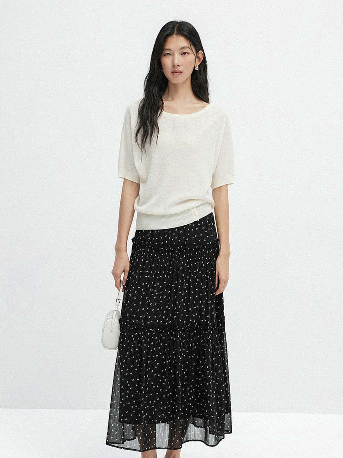 Front view of long black floral skirt featuring tiered construction and gathered waist