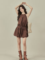 Close-up of brown halter neck dress with gathered waist detail.