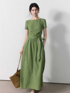 A woman wearing a sage green vertical-striped maxi dress with a tie belt.