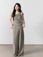 Full-length taupe grey wide-leg pants featuring side pockets and a tie belt.