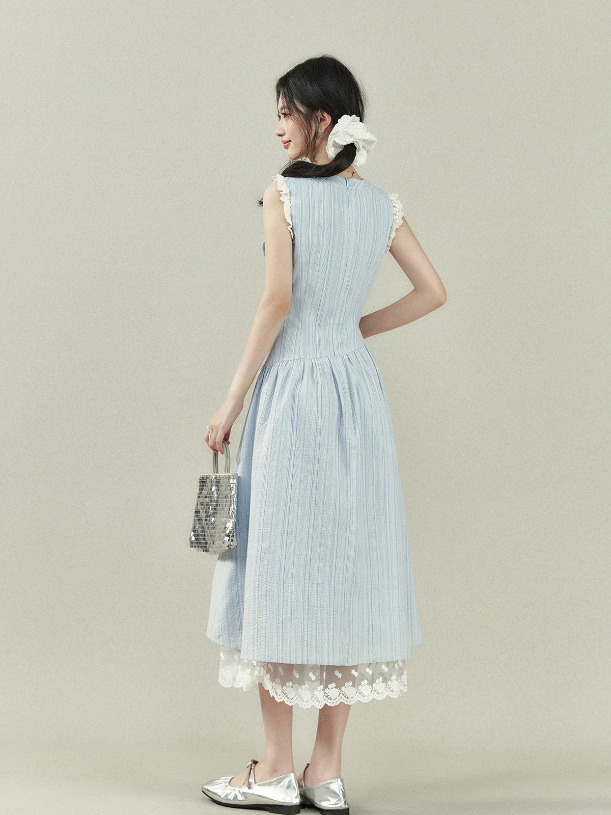Light blue dress with vertical stripes, lace trim on the shoulders and hem, a bow tie neckline, and an A-line silhouette.