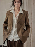 Front view of brown double-breasted blazer worn over a white shirt.