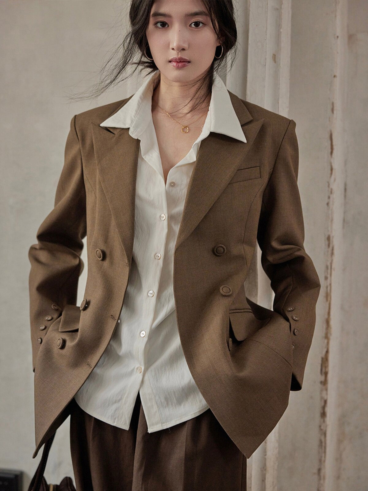 Front view of brown double-breasted blazer worn over a white shirt.