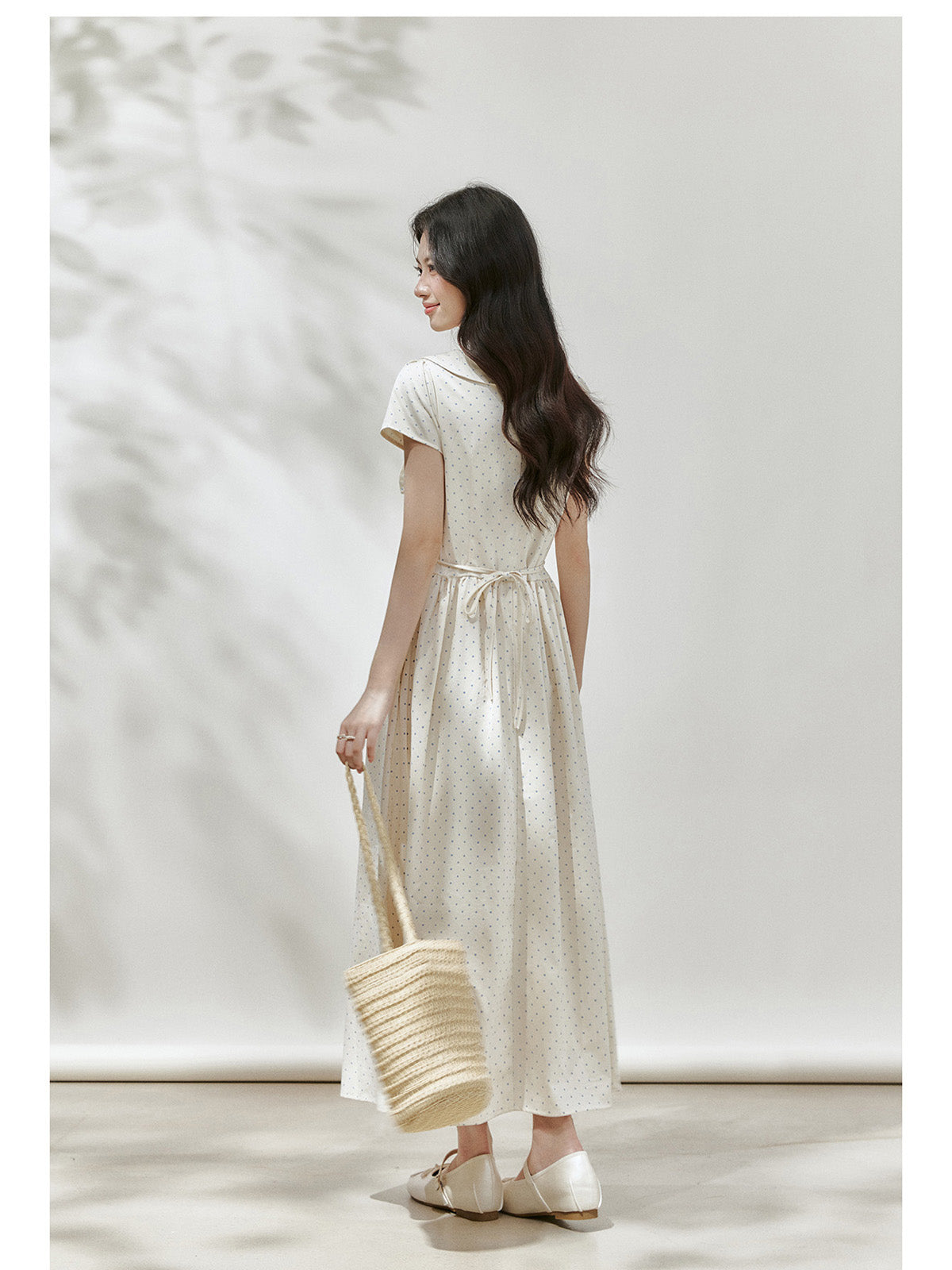 Ivory polka dot dress with a defined waist and straight hem.