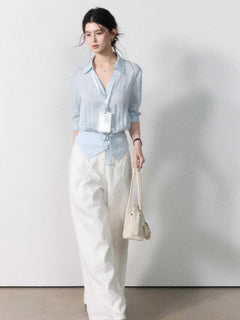 Mid-length light blue blouse with straight hem and gathered waist.