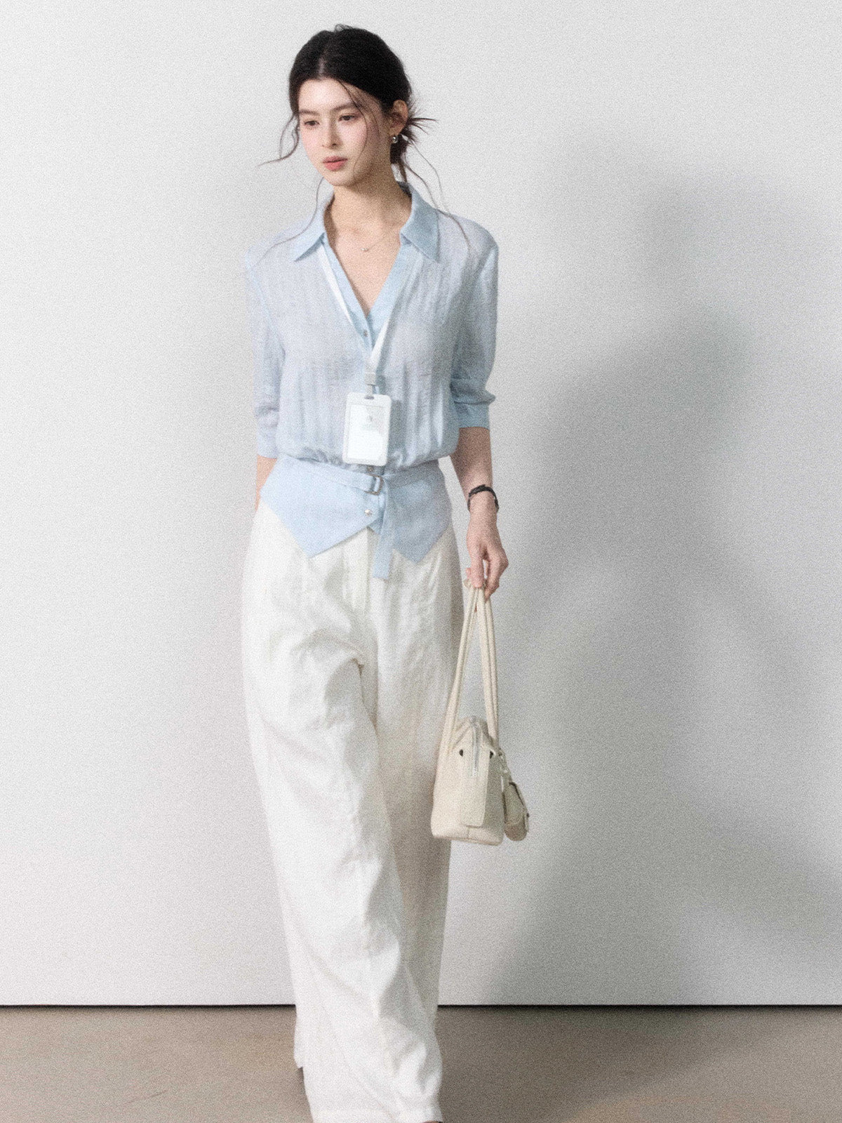 Mid-length light blue blouse with straight hem and gathered waist.