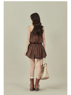 Back view of brown A-line dress showing pleated skirt and belt.