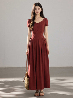 A woman in a red dress with a V-neck and front buttons, viewed from the side.