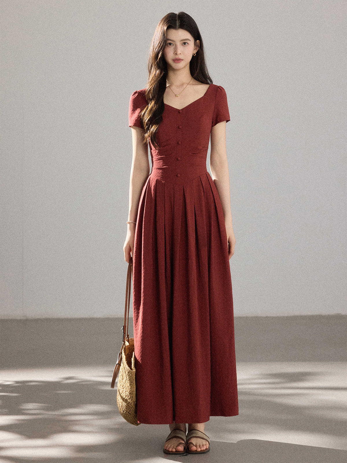 A woman in a red dress with a V-neck and front buttons, viewed from the side.