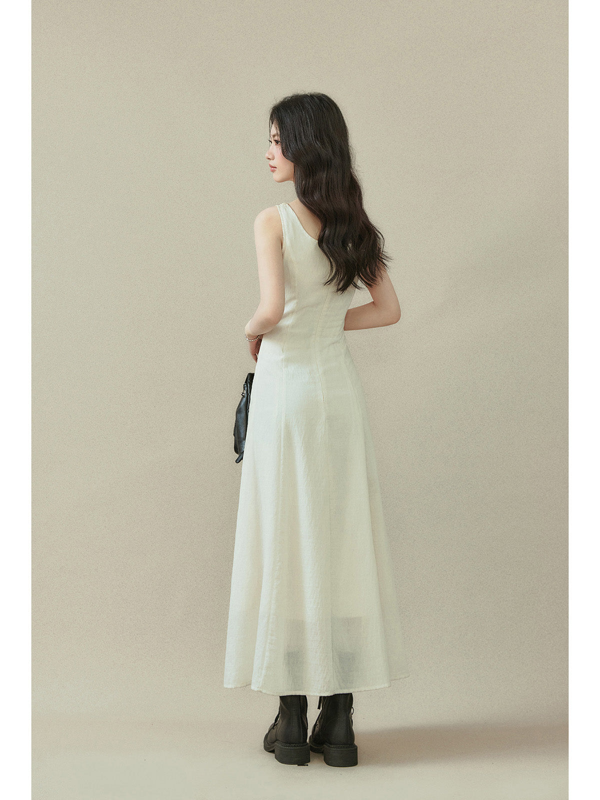 Ivory maxi dress with a straight hem, visible side pockets, and button details on the neckline.