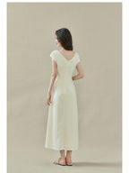 Cream off-shoulder dress with short sleeves, draped neckline, and side slit.