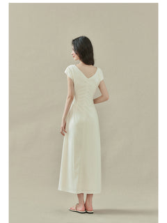 Cream off-shoulder dress with short sleeves, draped neckline, and side slit.