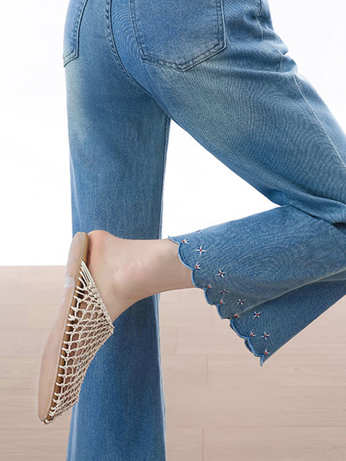 Side view showing high rise fit and side seams of light blue flared jeans.