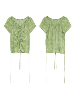 A flat lay shows a green tie-dye top from the front and back, highlighting its ruched design.