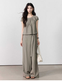 Front view of taupe grey wide-leg pants with a tie belt and side pockets.