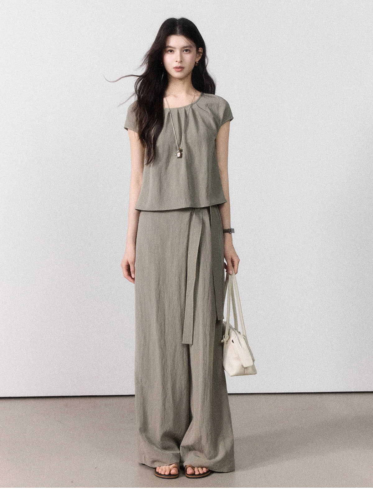 Front view of taupe grey wide-leg pants with a tie belt and side pockets.