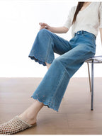 Detail of scalloped hem with embroidered stars on light blue flared jeans.