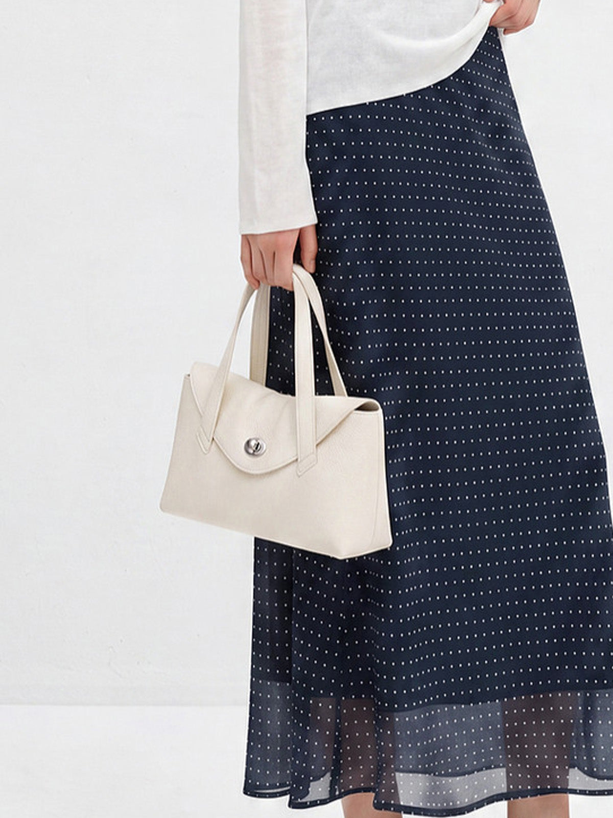 Navy polka dot A-line midi skirt shown from front with flared hem and high waist.