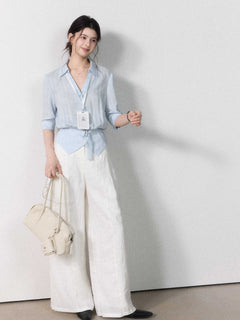 Fitted light blue blouse with collar, button closure, and tied belt.